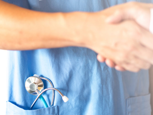 orthopedic surgeon handshaking with physician team or patient as ensure the confidence for good result healthcare with stethoscope in uniform. Medical business concept