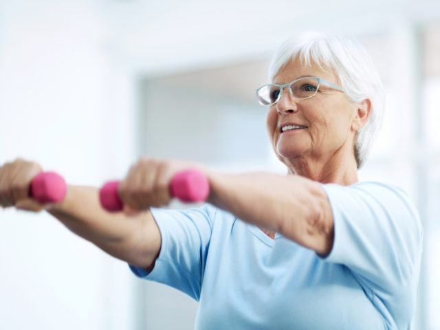senior woman working out using dumbbells at home
