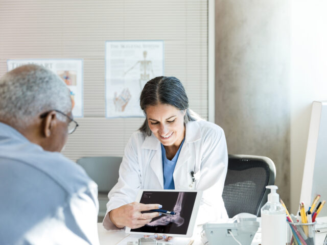 Orthopedic surgeon uses x-ray displayed on tablet to help patient
