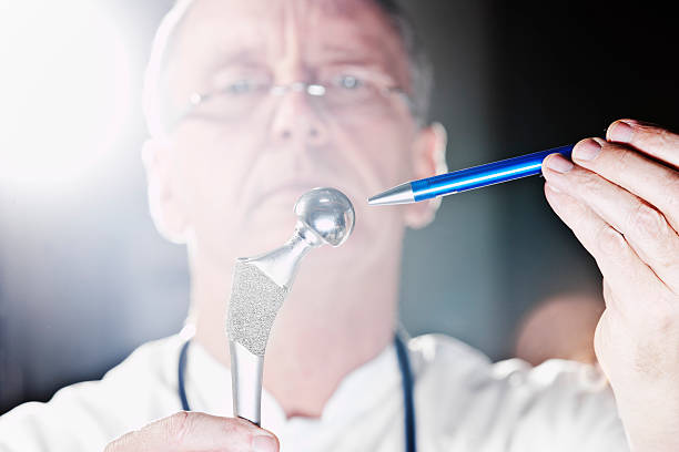 A male doctor, pointing at a total hip endoprothesis. XXL size image.