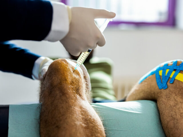 Sports medicine doctor Giving Knee Injection to the Patient
