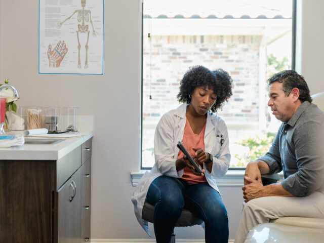 Female doctor points to something on tablet as patient listens
